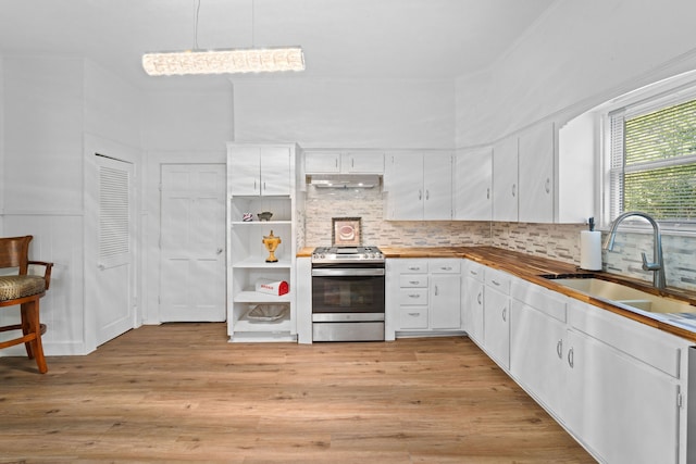 kitchen featuring white cabinets, sink, stainless steel stove, light hardwood / wood-style flooring, and tasteful backsplash