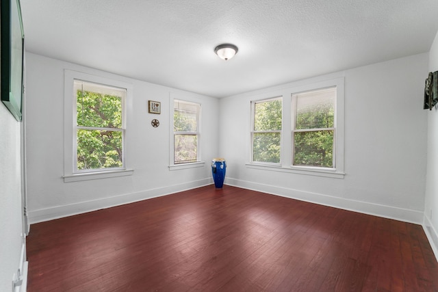 unfurnished room with a textured ceiling, dark hardwood / wood-style flooring, and a wealth of natural light