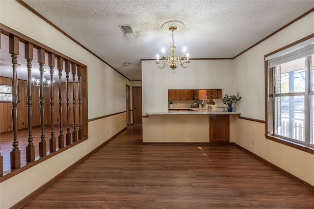 kitchen featuring hanging light fixtures, dark hardwood / wood-style floors, kitchen peninsula, a chandelier, and a textured ceiling