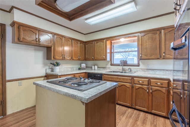 kitchen featuring light wood-type flooring, ornamental molding, sink, a kitchen island, and stainless steel gas stovetop