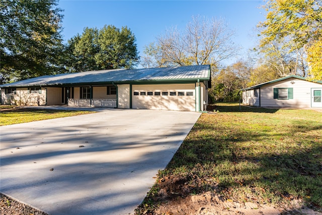 view of front of home featuring covered porch, a garage, and a front lawn