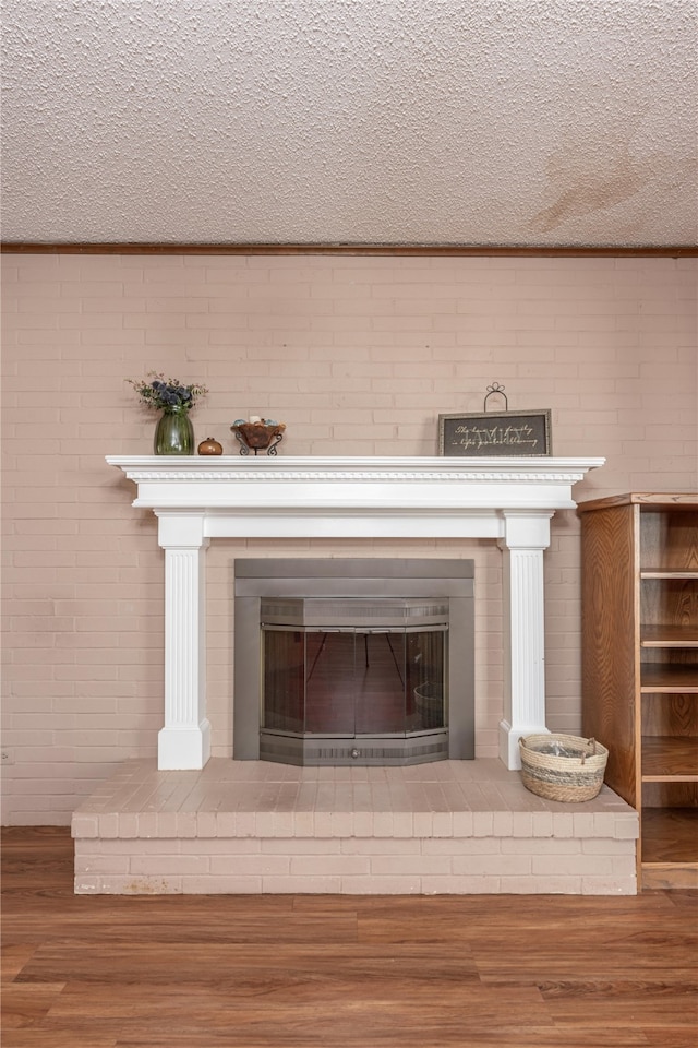 details featuring hardwood / wood-style floors, a textured ceiling, a brick fireplace, and ornamental molding