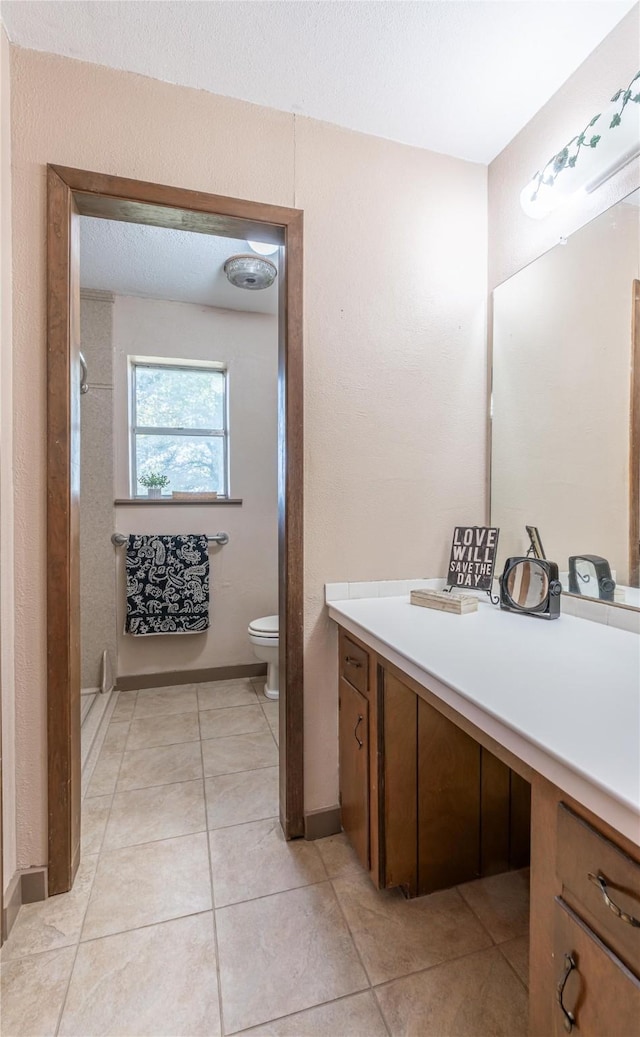 bathroom featuring tile patterned flooring, vanity, a textured ceiling, toilet, and walk in shower