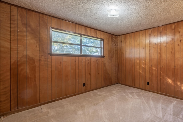 empty room with wood walls, light carpet, and a textured ceiling