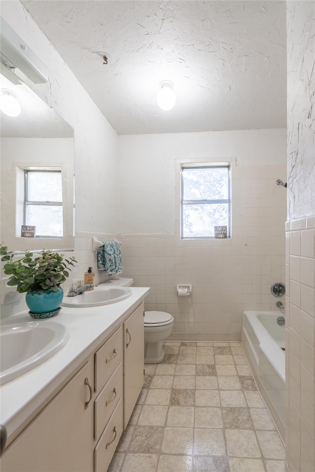 full bathroom featuring a wealth of natural light, vanity, and tile walls