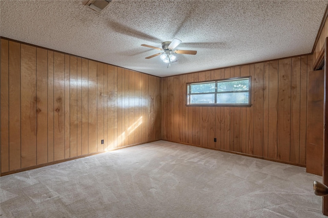 spare room featuring ceiling fan, light colored carpet, and a textured ceiling