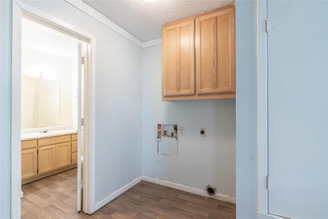 laundry room featuring cabinets, hookup for a washing machine, a textured ceiling, electric dryer hookup, and light hardwood / wood-style floors