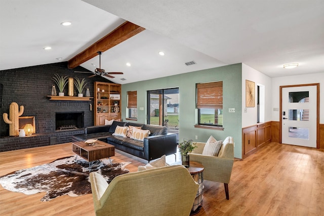 living room featuring vaulted ceiling with beams, ceiling fan, a fireplace, and light hardwood / wood-style flooring