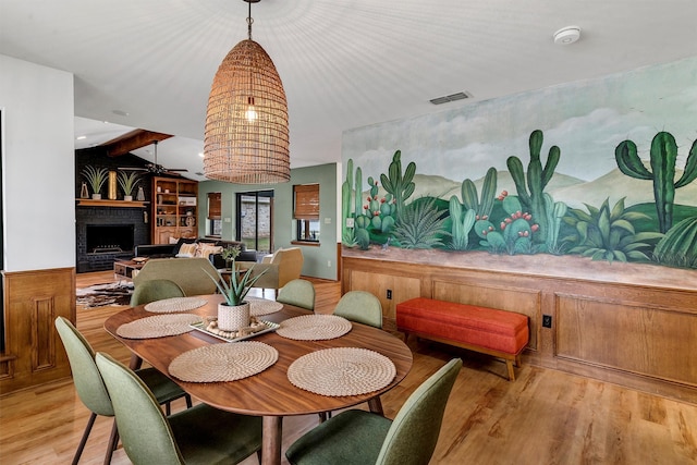 dining area with light wood-type flooring, a brick fireplace, and ceiling fan