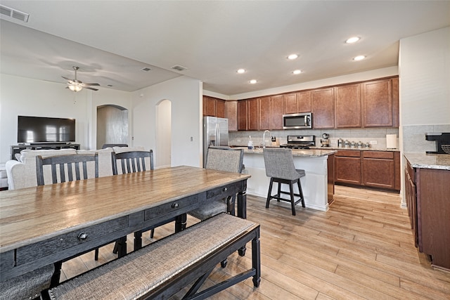 dining space with ceiling fan, light wood-type flooring, and sink