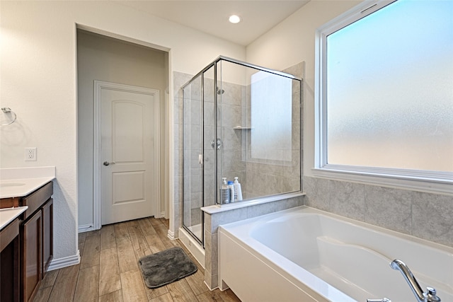 bathroom with vanity, hardwood / wood-style flooring, and plus walk in shower