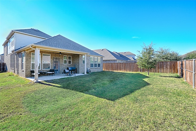 back of property with a lawn, ceiling fan, and a patio area