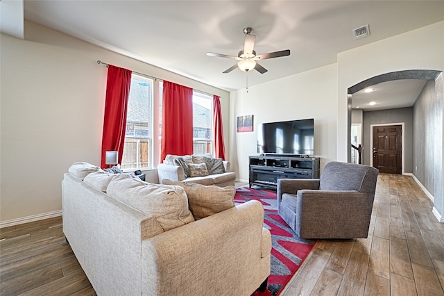 living room with ceiling fan and dark wood-type flooring