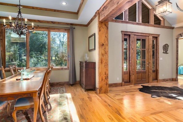 dining area with crown molding, lofted ceiling, a chandelier, and light hardwood / wood-style flooring