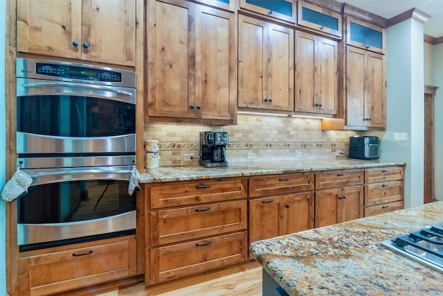 kitchen featuring light stone counters, tasteful backsplash, and appliances with stainless steel finishes