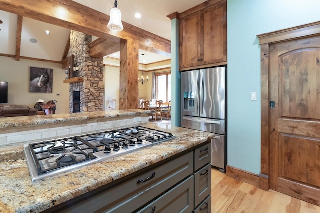 kitchen featuring light stone countertops, appliances with stainless steel finishes, a stone fireplace, and light hardwood / wood-style floors