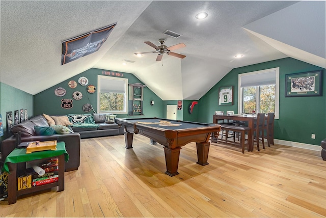 game room featuring lofted ceiling, plenty of natural light, light hardwood / wood-style floors, and a textured ceiling