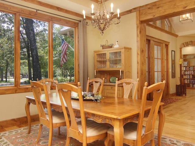 dining room with hardwood / wood-style floors, vaulted ceiling, and a chandelier