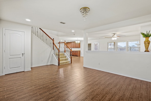 unfurnished living room with dark hardwood / wood-style floors and ceiling fan with notable chandelier