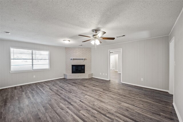 unfurnished living room featuring a textured ceiling, dark hardwood / wood-style floors, and a brick fireplace