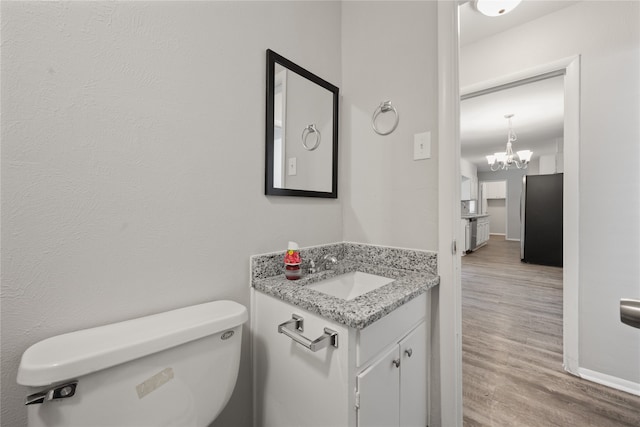 bathroom with a chandelier, vanity, hardwood / wood-style flooring, and toilet