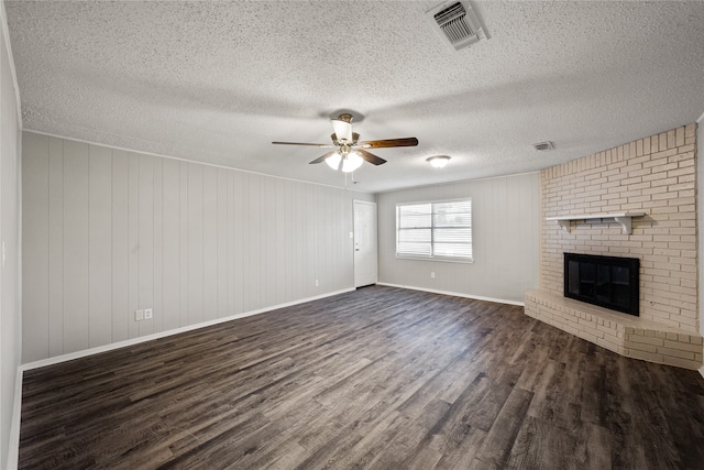 unfurnished living room featuring a fireplace, ceiling fan, dark hardwood / wood-style flooring, and a textured ceiling