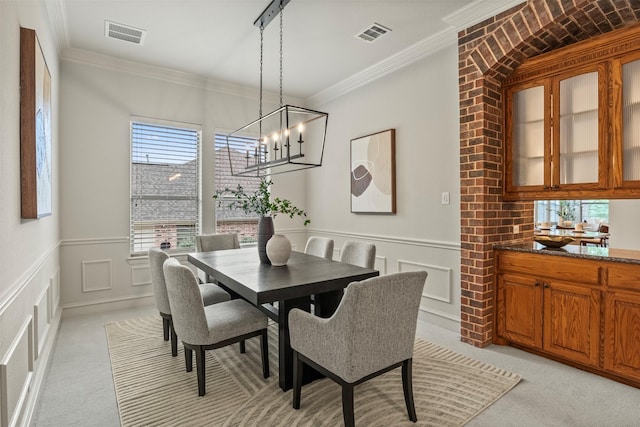 carpeted dining area featuring an inviting chandelier and ornamental molding