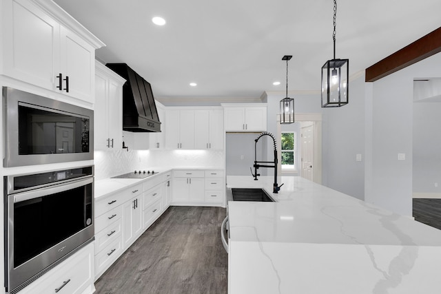 kitchen featuring white cabinetry, hanging light fixtures, custom range hood, and appliances with stainless steel finishes