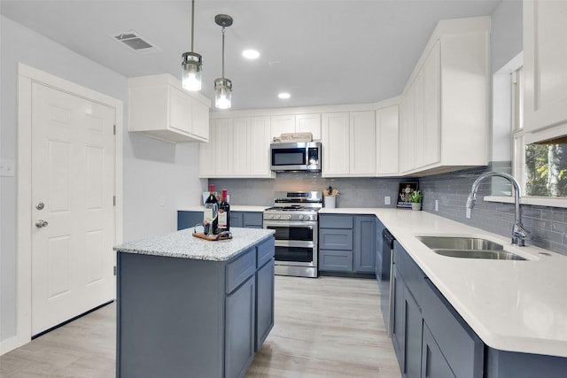 kitchen with a kitchen island, white cabinetry, appliances with stainless steel finishes, and decorative light fixtures