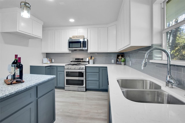 kitchen with pendant lighting, sink, gray cabinetry, stainless steel appliances, and white cabinets