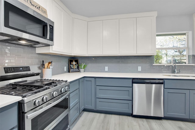 kitchen featuring white cabinetry, sink, light hardwood / wood-style flooring, and appliances with stainless steel finishes