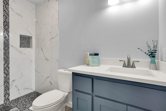 bathroom with vanity, tiled shower, and toilet