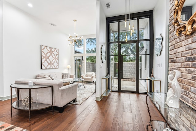 living room featuring an inviting chandelier, a towering ceiling, and dark wood-type flooring