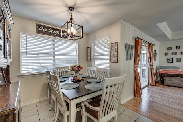 tiled dining area featuring a raised ceiling, an inviting chandelier, and crown molding