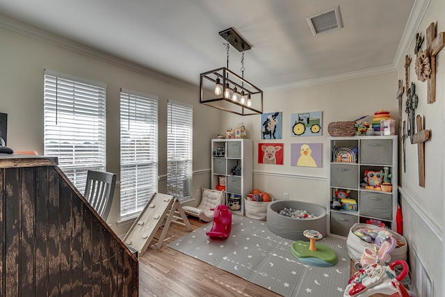 playroom featuring hardwood / wood-style floors, a chandelier, and ornamental molding