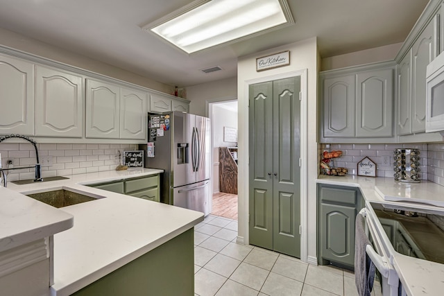 kitchen featuring light tile patterned flooring, range, decorative backsplash, and stainless steel fridge with ice dispenser