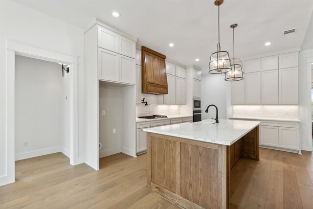 kitchen with tasteful backsplash, custom exhaust hood, stainless steel appliances, light hardwood / wood-style floors, and white cabinetry