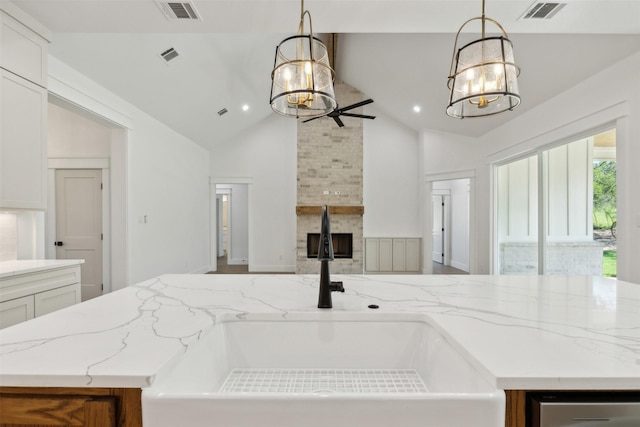 kitchen featuring sink, hanging light fixtures, a kitchen island, vaulted ceiling, and white cabinets