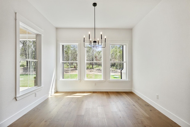 unfurnished dining area featuring hardwood / wood-style floors and a chandelier