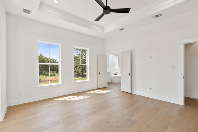 unfurnished bedroom with a raised ceiling, connected bathroom, light hardwood / wood-style flooring, and ceiling fan