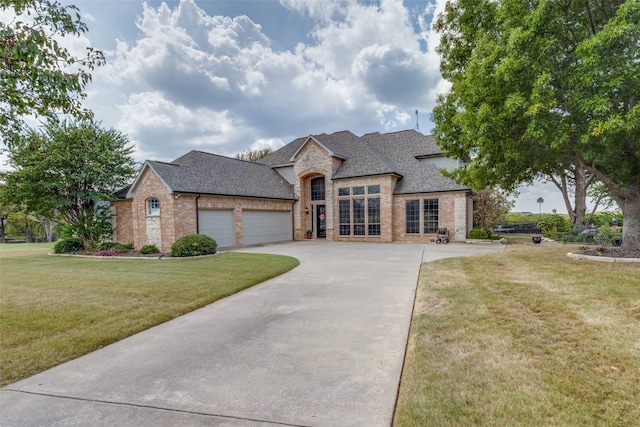 french provincial home with a garage and a front lawn