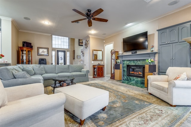 living room with a high end fireplace, ceiling fan, and ornamental molding