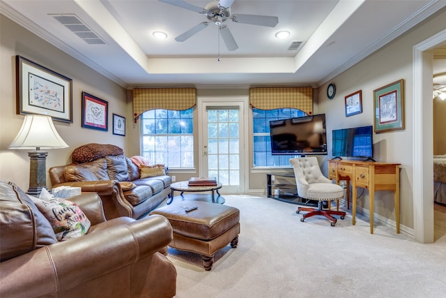 living room featuring a raised ceiling, light carpet, crown molding, and ceiling fan