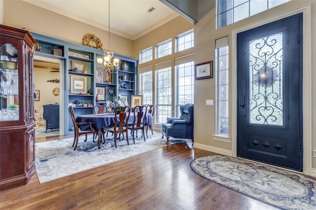 foyer with hardwood / wood-style floors, crown molding, and a notable chandelier