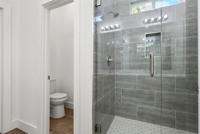 bathroom with hardwood / wood-style flooring, toilet, and an enclosed shower