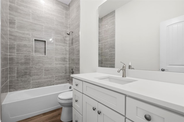 full bathroom featuring vanity, wood-type flooring, tiled shower / bath combo, and toilet