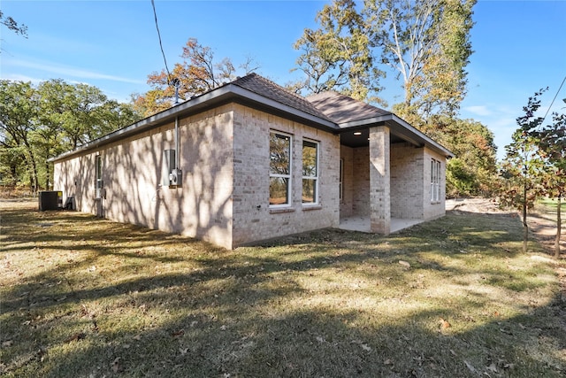 view of side of property with a patio area, a yard, and central air condition unit