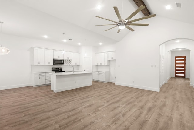 kitchen featuring high vaulted ceiling, a center island with sink, light wood-type flooring, appliances with stainless steel finishes, and white cabinetry