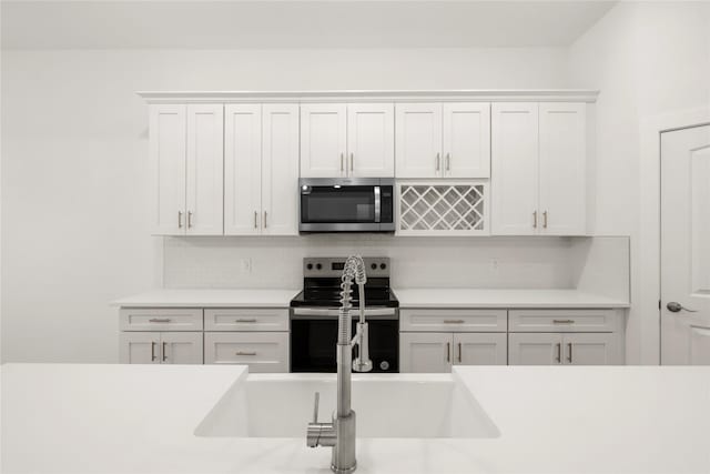 kitchen featuring sink, white cabinetry, backsplash, and appliances with stainless steel finishes