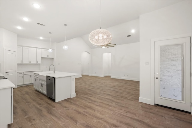 kitchen featuring dark hardwood / wood-style floors, decorative light fixtures, sink, white cabinets, and a center island with sink